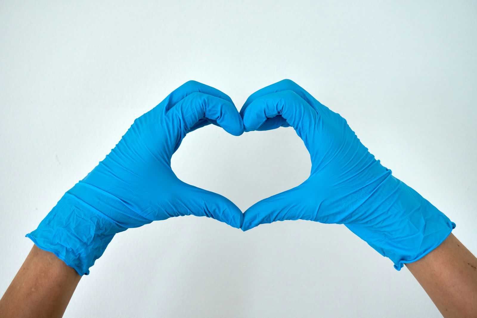 Two gloved hands forming a heart shape